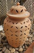 A large oriental style terracotta ginger jar with lid having pierced decoration, 75cm high, flanked