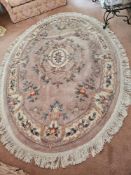 A 20th century oriental woollen rug in pink ground with floral pattern, 290 x 210cm.