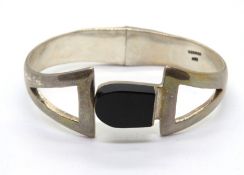 A substantial 925 silver bangle having black onyx central panel, 47.3g.