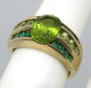 A 9ct gold ring having central oval cut peridot mounted over three rows of round cut peridot and