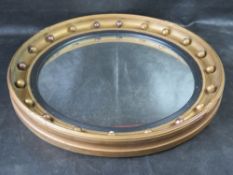 A mid century convex mirror with gilded frame.