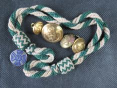 A quantity of brass military buttons together with a badge and a cap cord.