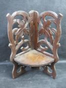 A black forest type carved wooden corner shelf having hinged shelf.