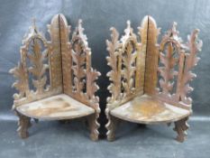 A pair of black forest type carved wooden corner shelves, each having hinged shelf.