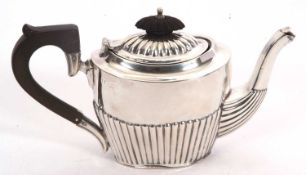An Edwardian silver bachelor teapot of oval form with part fluted decoration, ebonised finial and