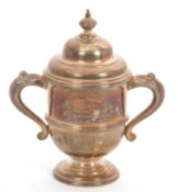A George V silver twin handle small lidded trophy with reeded decoration, engraved for the 