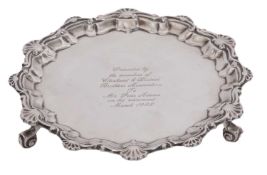 An Edwardian silver card salver, presentation engraved, having a moulded shell and scroll border and