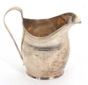 A George II silver cream jug of helmet shape having a reeded handle with foliate chased and engraved