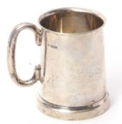 A George V silver pint tankard of plain tapering cylindrical form having a C scroll handle with a