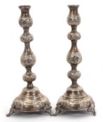 A pair of George V silver candlesticks of rounded form, with knopped baluster column and raised on