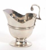 A Victorian silver helmet shaped cream jug of plain design with a cast scroll handle, a ribbed