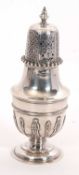 An Edwardian silver caster, the body with a strap work design and supported on a spreading foot,