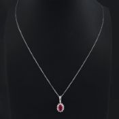 A 9CT WHITE GOLD RUBY AND DIAMOND CLUSTER PENDANT NECKLACE.