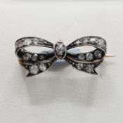 AN ANTIQUE WHITE AND YELLOW METAL DIAMOND BOW PIN BROOCH.