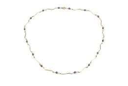 A 9ct gold fancy-link necklace, designed as a line of scroll-shaped links spaced by grey beads (
