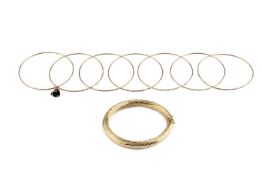A hinged oval bangle, of twisted design, stamped '750', together with a collection of slim
