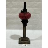 A 19th Century German brass corinthian oil lamp with ruby glass wrythen moulded fount. 13' high
