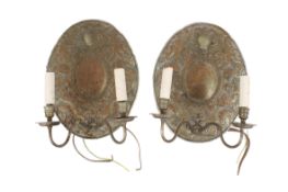 A pair of reproduction antique wall sconces. Having embossed oval back plate and two branches.