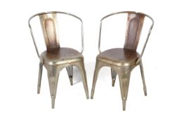 A pair of Tolix style stacking metal chairs with arms.