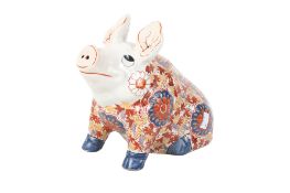 A Japanese pottery seated pig with red and blue decoration.