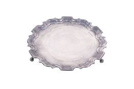 A small silver salver. With shaped border, undecorated, raised on three scrolling feet.