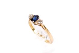 A hallmarked 18ct gold three stone ring. Set with one oval faceted sapphire of 0.
