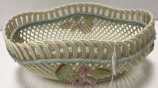 A Belleek basketwork bowl with applied floral spray decoration raised on a ropework foot bearing