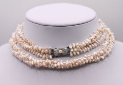 Mikimoto, a three strand fresh water pearl necklace, with maker mark on clasp.