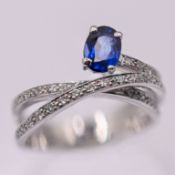 A diamond and sapphire 'twist' style ring, set in 14ct white gold, marked inside band D:0.32 C:0.78,