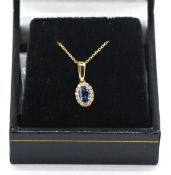 A 9ct yellow gold oval sapphire with round brilliant cut diamond cluster pendant on a 9ct yellow