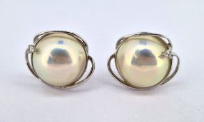 A pair of 14ct white gold pearl earrings, set with a small single diamond.