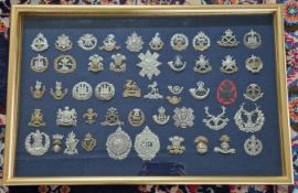 A large collection of WWI and WWII army cap badges, in two gilt display frames. (2)