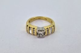 An 18ct yellow gold diamond ring, set with baguette cut diamonds and others to shoulders, size N.