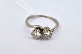 A diamond transitional brilliant cut two stone 'twist' ring set in white metal
