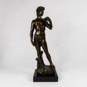A bronze figure of David after Michelangelo mounted on a black marble base, height 38.5cm.