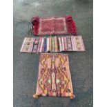 A rectangular Moroccan saddle cloth woven with lozenge motifs on red field, with braided fringes and