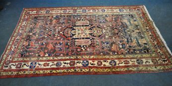A LARGE RECTANGULAR WOOLEN RUG, with mirrored and repeating geometric patterns, surrounded by a