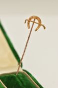 A YELLOW METAL STICK PIN, designed as a horse shoe and riding crop, stamped 15ct, approximate
