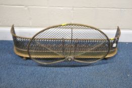 A BRASS FENDER, with pierced repeating patterns, width 100cm, along with a detachable peacock fan