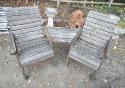 A PAIR OF WEATHERED TEAK GARDEN ARMCHAIRS, united by a shelf, each chair width 69cm x depth 75cm x