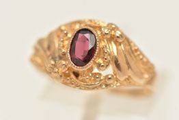 A 9CT GOLD GARNET RING, set with an oval cut garnet in a textured surround, polished band,