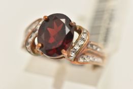 A BOXED 9CT GOLD GARNET AND DIAMOND RING, set with an oval cut garnet with single cut diamond