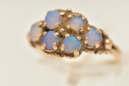 A YELLOW METAL OPAL RING, set with six worn opal cabochons, bifurcated shoulders and polished
