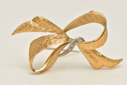 AN 18CT GOLD BROOCH, designed as a yellow gold bow with a white gold ribbon, set with three single