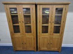 A PAIR OF MODERN LIGHT OAK DISPLAY CABINETS, with double glass doors, over double cupboard doors,