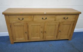 A MODERN LIGHT OAK SIDEBOARD, fitted with three drawers over four cupboard doors, the central drawer