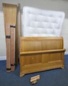 A MODERN LIGHT OAK 4FT6 SLEIGH BED, with side rails, slats, bolts, and central support, along with a