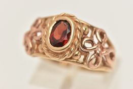 A BOXED 9CT GOLD 'CYM' GARNET RING, set with an oval cut garnet, collet set within an open work
