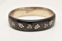 A WHITE METAL AND BACK ENAMEL HINGED BANGLE, grape and vine detailing set with split pearls, push