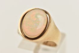 A YELLOW METAL WHITE OPAL CABOCHON RING, oval opal cabochon collet set within an open work surround,